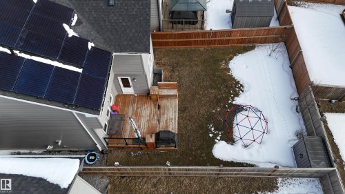 The property features solar panels on the roof, a spacious wooden deck, and a fenced yard with a lawn - 20503 99 Avenue, Edmonton, AB - Outdoor