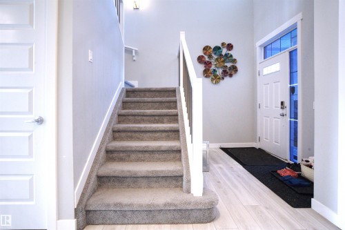 Entryway featuring a staircase with carpeting, light wood flooring, and a white front door with sidelight windows - 20503 99 Avenue, Edmonton, AB - Indoor Photo Showing Other Room