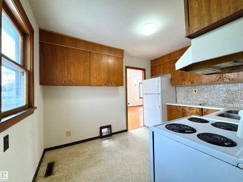 The kitchen features wood cabinetry, a white refrigerator, and a white oven with a stovetop - 12219 48 Street, Edmonton, AB - Indoor Photo Showing Kitchen