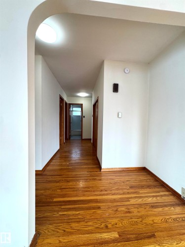 Hallway featuring hardwood floors, white walls, and an arched entryway - 12219 48 Street, Edmonton, AB - Indoor Photo Showing Other Room