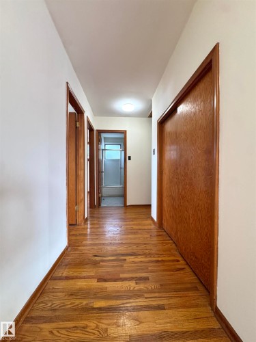 The hallway features hardwood flooring, white walls, and wood doors, with an overhead light fixture providing illumination - 12219 48 Street, Edmonton, AB - Indoor Photo Showing Other Room