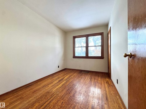 This room features hardwood floors and a window with wood trim - 12219 48 Street, Edmonton, AB - Indoor Photo Showing Other Room