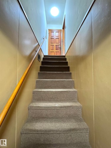 Staircase featuring carpeted steps and a wooden handrail - 12219 48 Street, Edmonton, AB - Indoor Photo Showing Other Room