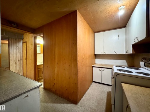 Kitchen area with white cabinetry, a stovetop, and wood paneled walls - 12219 48 Street, Edmonton, AB - Indoor Photo Showing Kitchen