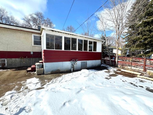 The property features a sunroom with large windows and a red and white exterior, complemented by an exterior wall with stucco finish - 12219 48 Street, Edmonton, AB - Outdoor