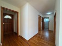 This property features hardwood flooring throughout the hallway and a solid wood front door with an arched window - 12219 48 Street, Edmonton, AB  - Indoor Photo Showing Other Room 