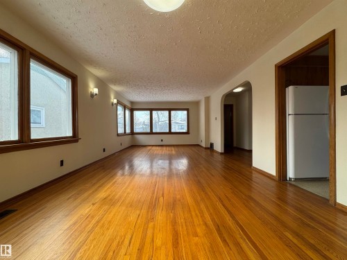 The property features hardwood floors, light-colored walls, and numerous windows with wood trim - 12219 48 Street, Edmonton, AB - Indoor Photo Showing Other Room