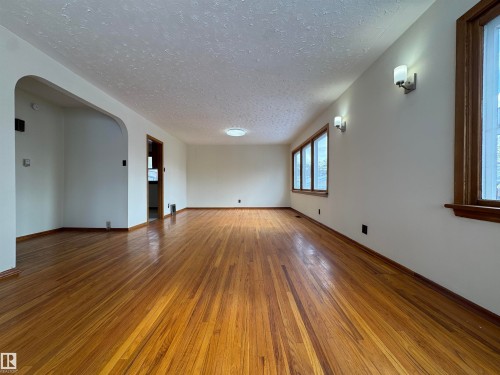 The property features hardwood floors, a bright interior with multiple windows, and wall-mounted light fixtures - 12219 48 Street, Edmonton, AB - Indoor Photo Showing Other Room