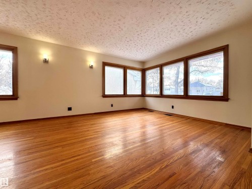 This room features hardwood floors and a corner window arrangement providing views of the surrounding area - 12219 48 Street, Edmonton, AB - Indoor Photo Showing Other Room