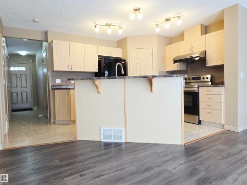 The kitchen features light-toned cabinetry - 60 1128 156 Street, Edmonton, AB - Indoor Photo Showing Kitchen