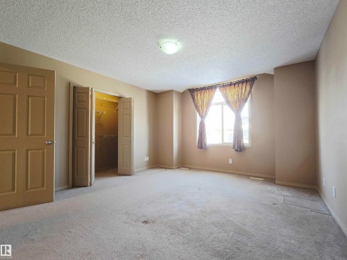This spacious room features carpeted flooring, a window providing natural light, and a closet with bifold doors - 60 1128 156 Street, Edmonton, AB - Indoor Photo Showing Other Room