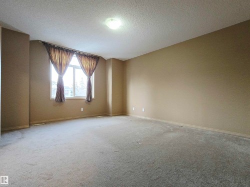 Spacious room featuring neutral-toned walls, light-colored carpeting, a large window, and a ceiling-mounted light fixture - 60 1128 156 Street, Edmonton, AB - Indoor Photo Showing Other Room