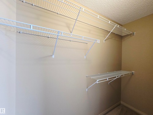 The primary bedroom features a closet with wire shelving providing storage solutions - 60 1128 156 Street, Edmonton, AB - Indoor With Storage