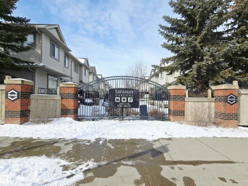 The complex features a fence with brick pillars and a wrought iron gate - 60 1128 156 Street, Edmonton, AB - Outdoor With Deck Patio Veranda