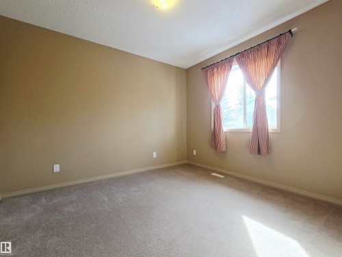 This bedroom features neutral-toned walls, carpeted flooring, and a window providing natural light - 60 1128 156 Street, Edmonton, AB - Indoor Photo Showing Other Room