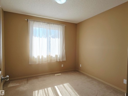 This room features neutral-toned walls, carpeted flooring, and a window with sheer curtains - 60 1128 156 Street, Edmonton, AB - Indoor Photo Showing Other Room