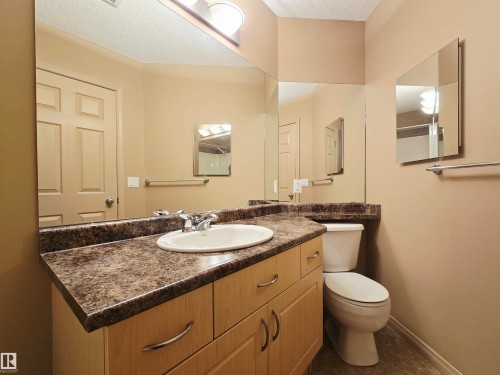 Bathroom featuring an extensive vanity with a built-in sink, a large mirror, a toilet, and linoleum flooring - 60 1128 156 Street, Edmonton, AB - Indoor Photo Showing Bathroom