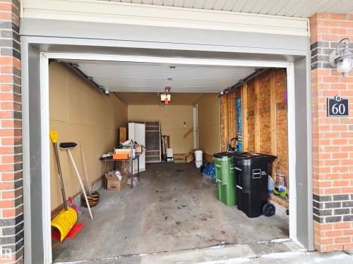 The property features an attached garage with a concrete floor, brick exterior, and an exterior light fixture - 60 1128 156 Street, Edmonton, AB - Indoor Photo Showing Garage