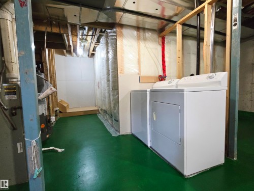 Utility area featuring a washer and dryer, exposed ceiling joists, and a green painted floor - 60 1128 156 Street, Edmonton, AB - Indoor Photo Showing Other Room
