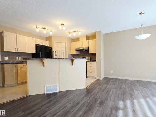 Kitchen and dining area featuring light-toned cabinetry, dark countertops - 60 1128 156 Street, Edmonton, AB - Indoor Photo Showing Kitchen