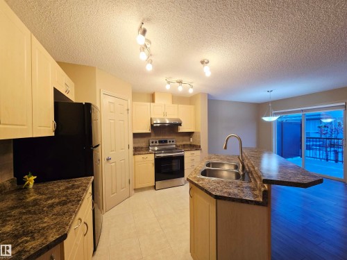 The kitchen features light-toned cabinetry and ample counter space with a double basin sink - 60 1128 156 Street, Edmonton, AB - Indoor Photo Showing Kitchen With Double Sink