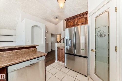 Kitchen featuring a stainless steel Bosch dishwasher, a stainless steel refrigerator, and a pantry with a frosted glass door - 10631 181 Avenue, Edmonton, AB - Indoor