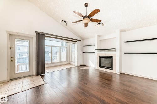 Living area featuring hardwood flooring, a fireplace with tile surround, built-in shelving, and a ceiling fan - 10631 181 Avenue, Edmonton, AB - Indoor Photo Showing Living Room With Fireplace