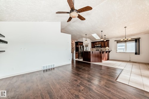 The open concept living area features dark hardwood flooring, a vaulted ceiling, and a ceiling fan - 10631 181 Avenue, Edmonton, AB - Indoor