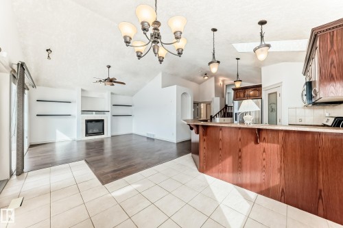 Open concept living space featuring a fireplace, a ceiling fan, and hardwood flooring - 10631 181 Avenue, Edmonton, AB - Indoor Photo Showing Kitchen