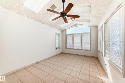 This room features tiled flooring, a ceiling fan with light fixture, and large windows with blinds that provide natural light - 10631 181 Avenue, Edmonton, AB - Indoor Photo Showing Other Room