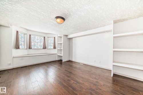 This room features hardwood floors, a bay window with a built-in bench, and integrated shelving units - 10631 181 Avenue, Edmonton, AB - Indoor Photo Showing Other Room