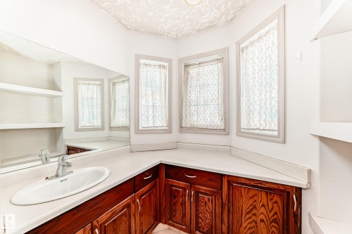 Vanity area featuring a built-in sink with chrome faucet, rich wood cabinetry, and a countertop - 10631 181 Avenue, Edmonton, AB - Indoor Photo Showing Bathroom
