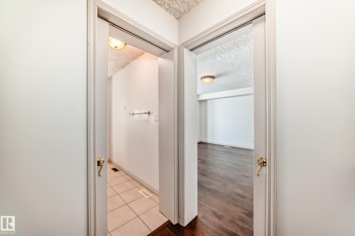 Hallway featuring two doorways, one leading to a room with tiled flooring and a wall-mounted towel bar, and the other opening to a room with dark wood flooring - 10631 181 Avenue, Edmonton, AB - Indoor Photo Showing Other Room