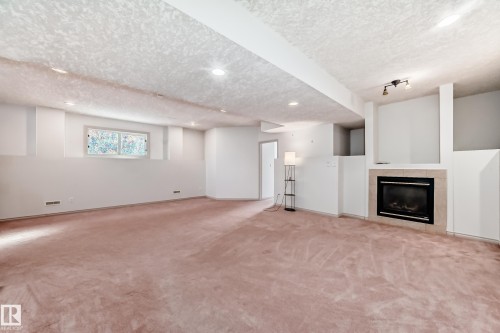 Expansive room featuring recessed lighting, a window providing natural light, and a fireplace with a light-colored surround - 10631 181 Avenue, Edmonton, AB - Indoor With Fireplace