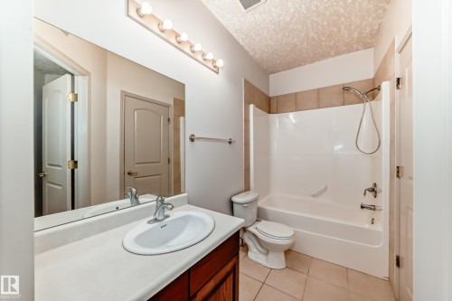 Bathroom featuring a vanity with a countertop sink, a mirror with overhead lighting, and a shower/tub combination with tiled surround - 10631 181 Avenue, Edmonton, AB - Indoor Photo Showing Bathroom