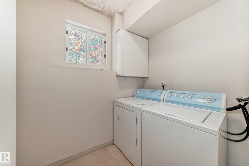The laundry area features a window with decorative glass, a white wall-mounted cabinet, and light-colored walls - 10631 181 Avenue, Edmonton, AB - Indoor Photo Showing Laundry Room