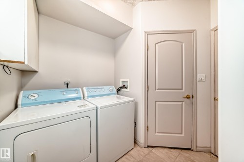 This utility area features a washing machine and dryer, a storage cabinet, and tiled flooring - 10631 181 Avenue, Edmonton, AB - Indoor Photo Showing Laundry Room