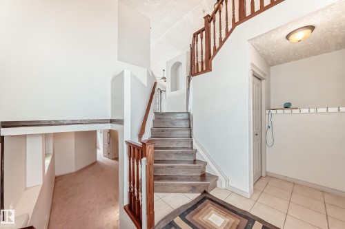 The property features a staircase with wood treads and banisters, complemented by a tiled entryway - 10631 181 Avenue, Edmonton, AB - Indoor Photo Showing Other Room