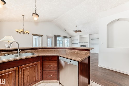 The kitchen features a double basin sink, dark wood cabinetry, and a stainless steel dishwasher - 10631 181 Avenue, Edmonton, AB - Indoor Photo Showing Kitchen With Double Sink