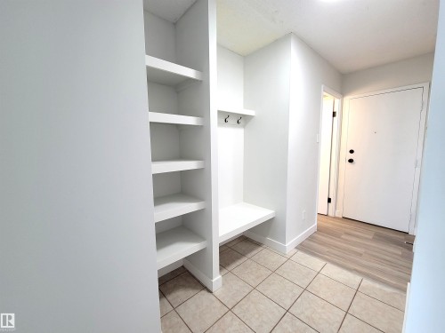 Entryway featuring tiled flooring, built-in shelving, and a bench with coat hooks - 804 9028 Jasper Avenue, Edmonton, AB - Indoor
