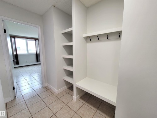 Entryway featuring tile flooring, built-in shelving, a bench, and wall-mounted hooks - 804 9028 Jasper Avenue, Edmonton, AB - Indoor