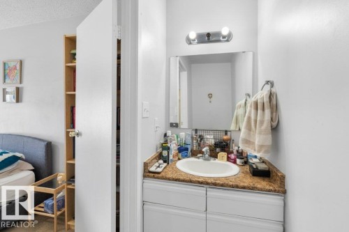 The bathroom features a vanity with a countertop and integrated sink, illuminated by a wall-mounted light fixture - 638 Saddleback Road, Edmonton, AB - Indoor Photo Showing Bathroom