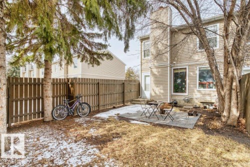 The property features a private yard with a paved patio area, a wooden fence, and mature trees - 638 Saddleback Road, Edmonton, AB - Outdoor