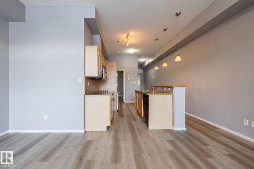 Open concept living space featuring light gray walls, light wood flooring, and recessed lighting - 210 10147 112 Street, Edmonton, AB - Indoor Photo Showing Kitchen