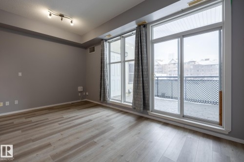The room features light-toned flooring, gray walls, and a track lighting fixture on the ceiling - 210 10147 112 Street, Edmonton, AB - Indoor Photo Showing Other Room