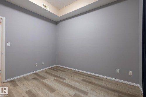 The room features light wood-style flooring, light grey walls, and white baseboards - 210 10147 112 Street, Edmonton, AB - Indoor Photo Showing Other Room