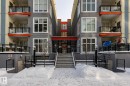The property features a building with a gray and cream facade, accented by orange-colored balconies - 210 10147 112 Street, Edmonton, AB  - Outdoor With Balcony With Facade 