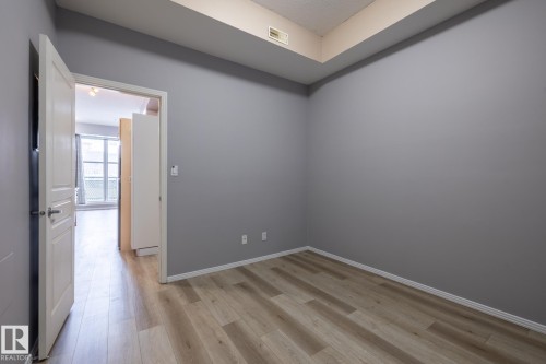 This room features light wood-style flooring, grey painted walls, and white trim - 210 10147 112 Street, Edmonton, AB - Indoor Photo Showing Other Room