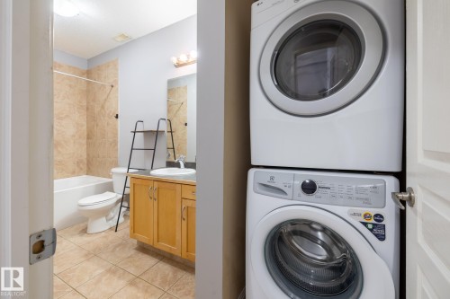 The property features a bathroom with a bathtub, a toilet, a vanity with a sink, and a mirror - 210 10147 112 Street, Edmonton, AB - Indoor Photo Showing Laundry Room