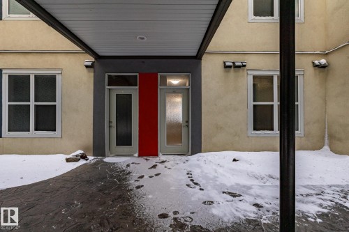The property features a stucco exterior with multiple windows and two entry doors - 210 10147 112 Street, Edmonton, AB - Outdoor With Exterior